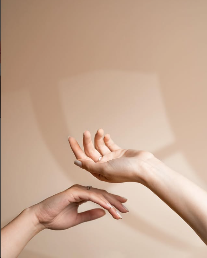 Two softly lit hands with neutral manicures